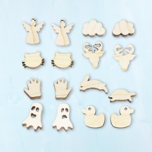 May include: A set of 14 wooden cutout shapes, including angels, clouds, cats, hands, a rabbit, a turtle, ghosts, and ducks. The shapes are all made of natural wood and have a light brown color.