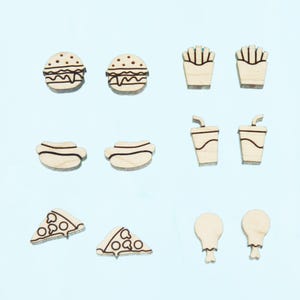 May include: A set of 10 wooden earrings featuring various fast food icons, including a burger, fries, hot dog, pizza slice, chicken drumstick, and a soda cup. The earrings are all unpainted and have a natural wood finish.
