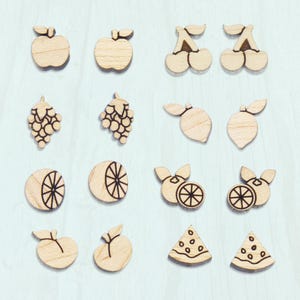 May include: A set of 12 wooden fruit and food earrings. The earrings are laser cut and feature a variety of fruits, including apples, cherries, grapes, lemons, oranges, and watermelon.