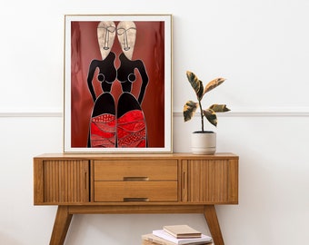 May include: Framed artwork featuring two stylized figures with black bodies, white faces, and red and black patterned skirts. The artwork is displayed on a mid-century modern wooden cabinet. A small potted plant and a wooden stool are also in the image.