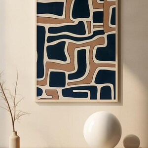 May include: Abstract art print with a geometric pattern in shades of brown and blue. The print is framed and hanging on a wall.