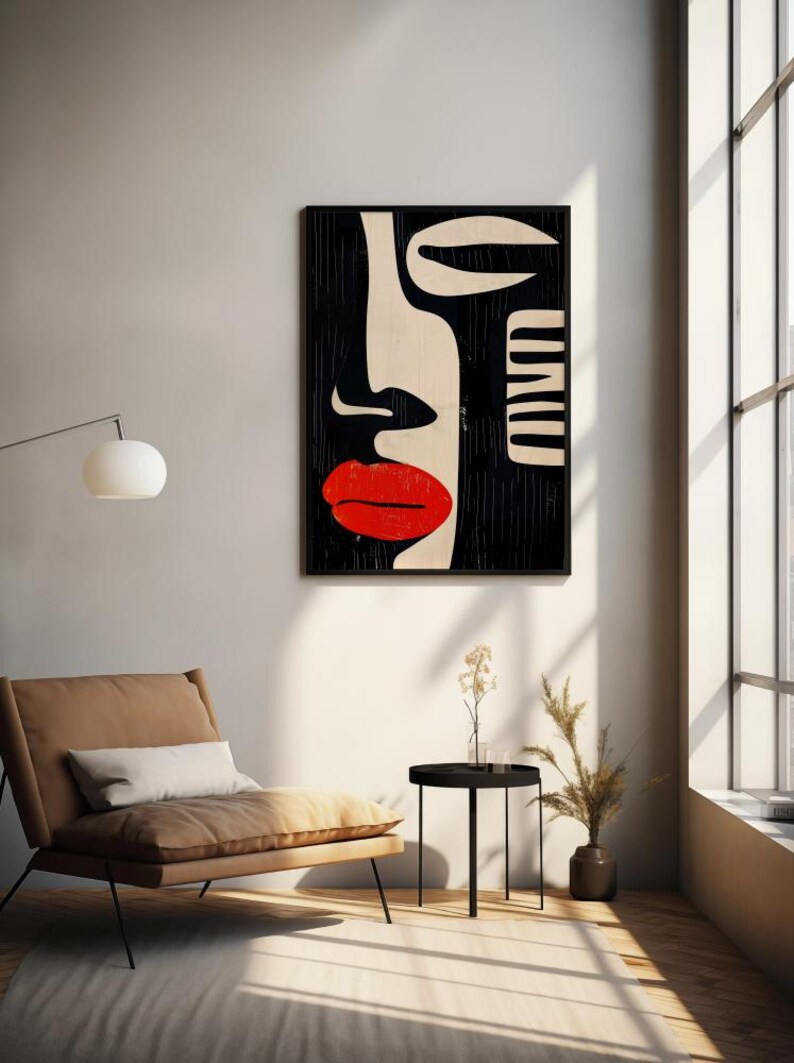 May include: Abstract art print featuring a black and white stylized face with a red lip. The print is framed and hanging on a white wall.