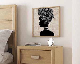 May include: A framed wall art print featuring a black silhouette of a woman with an elaborate head wrap. The artwork is set against a light-colored background with a wood grain texture. The frame is a light brown color.