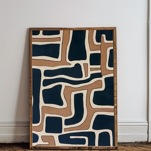 May include: Abstract art print with a geometric pattern in shades of brown, beige, and navy blue. The print is framed in a natural wood frame.