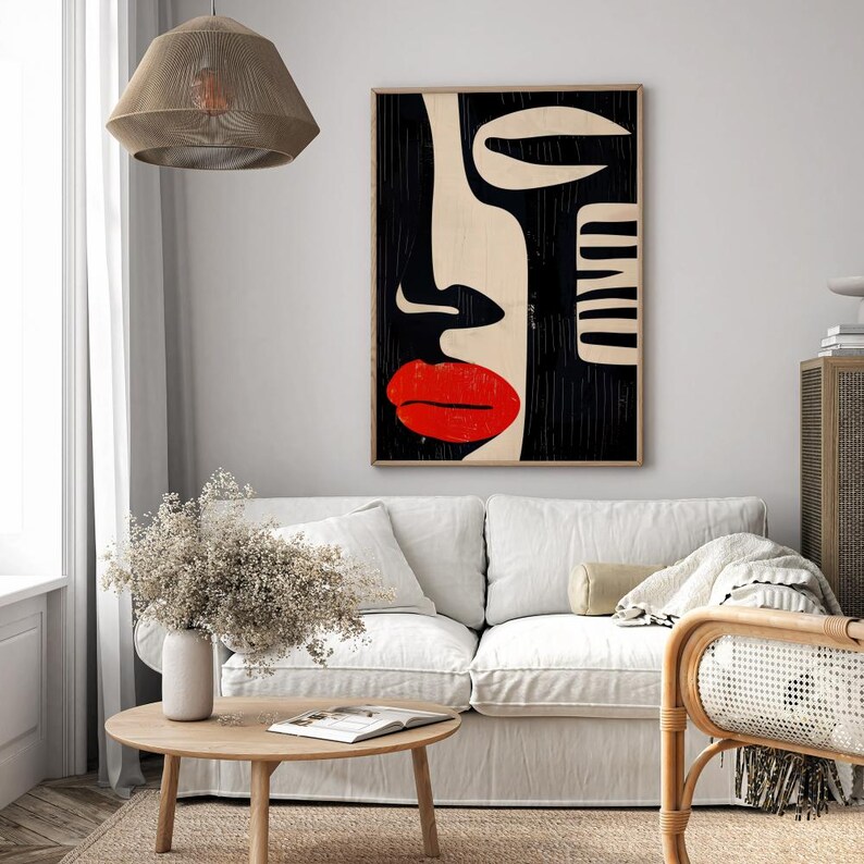 May include: Abstract art print featuring a black and white stylized face with a red lip. The print is framed and hanging on a white wall.