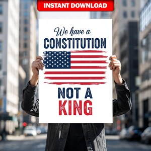Pode incluir: Um cartaz branco com o texto "We have a CONSTITUTION NOT A KING" e uma bandeira americana estilizada. O cartaz é segurado em frente a um fundo urbano desfocado. As palavras "INSTANT DOWNLOAD" estão em uma faixa vermelha no topo.