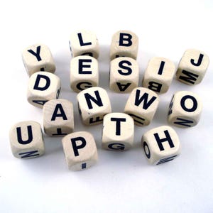 May include: A collection of wooden letter dice with black uppercase letters. The dice are scattered on a white surface, with various letters visible, including "U", "D", "A", "N", "T", "P", "W", "O", "H", "J", "B", "S", "I", "L", and "E".