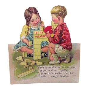 May include: Vintage Valentine's Day card featuring two children building a house with toy blocks. The card has the text "FOR MY VALENTINE" on the building and a poem below. The boy is wearing a red striped shirt and the girl is wearing a blue dress.