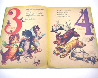 May include: Vintage children's book open to two pages. One page features the number 3 in red with three kittens wearing mittens. The other page shows the number 4 in purple with four puppies. Text accompanies each illustration.