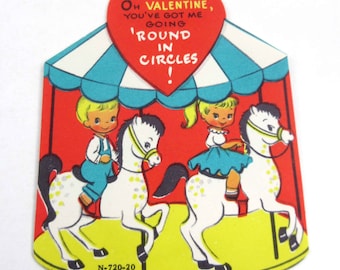 Carte Saint-Valentin vintage pour enfants avec une fille et un garçon blonds sur des chevaux de manège, parc d'attractions de carnaval