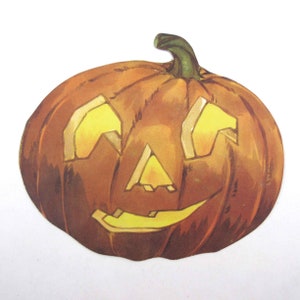 May include: A vintage Halloween jack-o'-lantern cutout with a smiling face. The pumpkin is orange with yellow eyes, nose, and mouth.