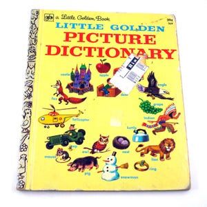 May include: A vintage Little Golden Book titled "Little Golden Picture Dictionary" with colorful illustrations of various objects and animals. The cover is yellow with red and blue text, and a price tag is affixed to the top right corner.