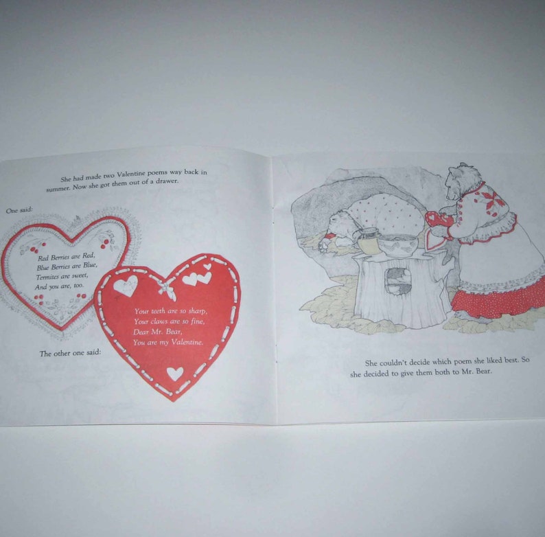 May include: An open book with illustrations and text. Two red heart-shaped Valentine's Day poems are on the left page. The right page shows a bear and a woman bear. The text reads, "Red Berries are Red, Blue Berries are Blue, Termites are sweet, And you are, too."