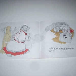 May include: An open book illustration featuring a bear character in a white dress with red trim, carrying a container. The opposite page shows a bear sleeping near a tree stump. Text reads, "She carried the can of ice water inside..."
