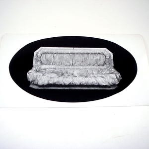 May include: A black and white image of a small, rectangular, satin-like object, possibly a purse or clutch, with a pleated design. The object is set against a black oval background, which is on a white rectangular card.