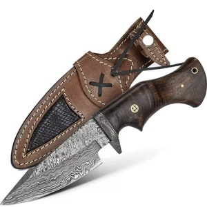 May include: A brown leather sheath with a black leather lining and a brown leather strap with a metal button. A knife with a dark wood handle and a patterned steel blade is in the sheath.