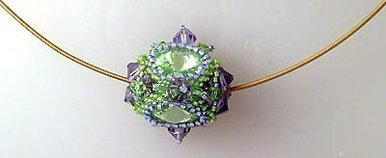 K&ouml;nnte beinhalten: Ein gr&uuml;ner und violetter Perlenanh&auml;nger mit einer goldenen Kette. Der Anh&auml;nger ist eine Kugel mit einem facettierten Design.