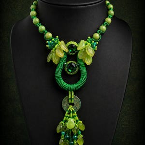 May include: A beaded necklace featuring green round beads, two dark green faceted stones, and a central green wrapped ring. The design includes light green leaf-shaped beads and two circular metal coins. Text reads: If Money Grew on Trees Necklace PDF Tutorial For personal use only HANNAH ROSNER.