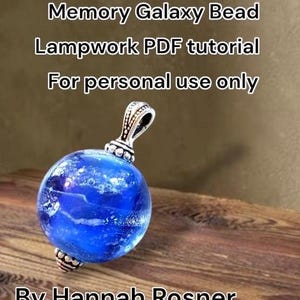 May include: A blue Memory Galaxy bead pendant with a silver-coloured bail. The bead has a galaxy-like design with white and blue swirls. The text on the image reads "Memory Galaxy Bead Lampwork PDF tutorial For personal use only By Hannah Rosner."