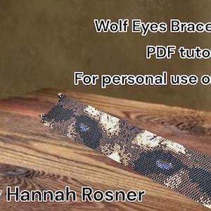 Op de afbeelding: Een kralenarmband met een wolfsoogontwerp, met tinten bruin, zwart en wit. De tekst "Wolf Eyes Bracelet PDF tutorial" en "For personal use only" wordt weergegeven. De armband ligt op een houten oppervlak.