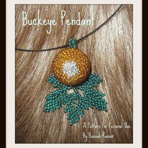 Może przedstawiać: Złoty i zielony koralikowy wisiorek w kształcie orzecha buckeye, z tekstem "Buckeye Pendant" i "A Pattern For Personal Use By Hannah Rosner" na obrazku.