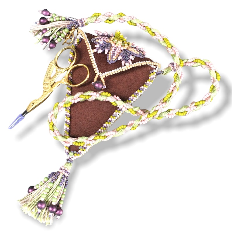 May include: A brown triangular needle case with a beaded border and a floral design. The case has a gold pair of scissors attached to it and a long beaded cord with tassels at each end.
