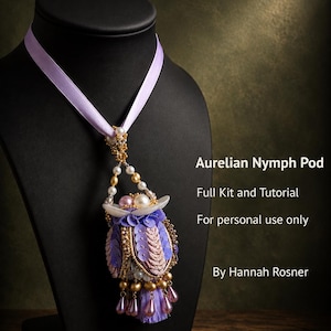 Könnte beinhalten: Eine Anhängerkette mit einem lavendelfarbenen Band und einem dekorativen Kapsel-Ornament, verziert mit violetten Pailletten, goldenen Perlen und perlmuttartigen Akzenten. Der Text lautet: Aurelian Nymph Pod, Full Kit and Tutorial, For personal use only, By Hannah Rosner.