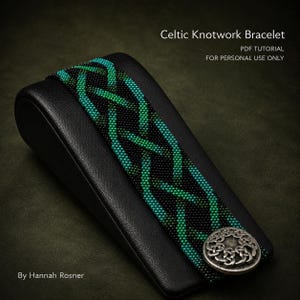 Puede incluir: Una pulsera de cuentas con un patrón de nudos celtas en tonos negro, verde esmeralda y azul cerceta. La pulsera se asegura con un cierre de botón de metal plateado grabado con un diseño de nudo circular. El texto dice Celtic Knotwork Bracelet.