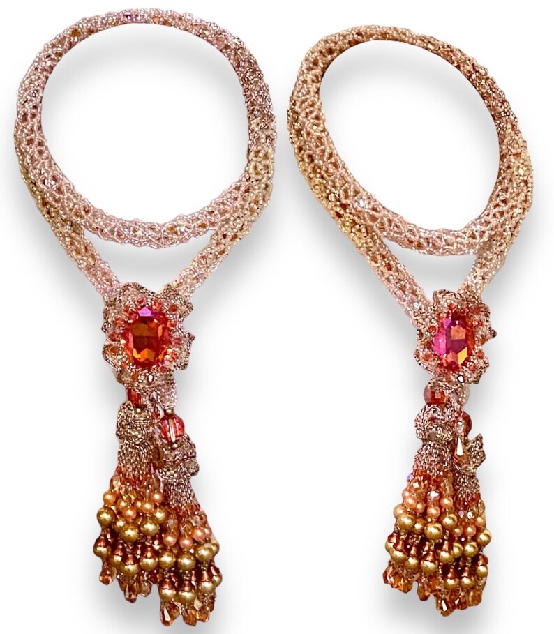 May include: Two beaded necklaces with a circular design. Each necklace features a large, oval-shaped orange gemstone pendant, intricate beadwork, and a tassel of golden beads. The necklaces are displayed against a white background.