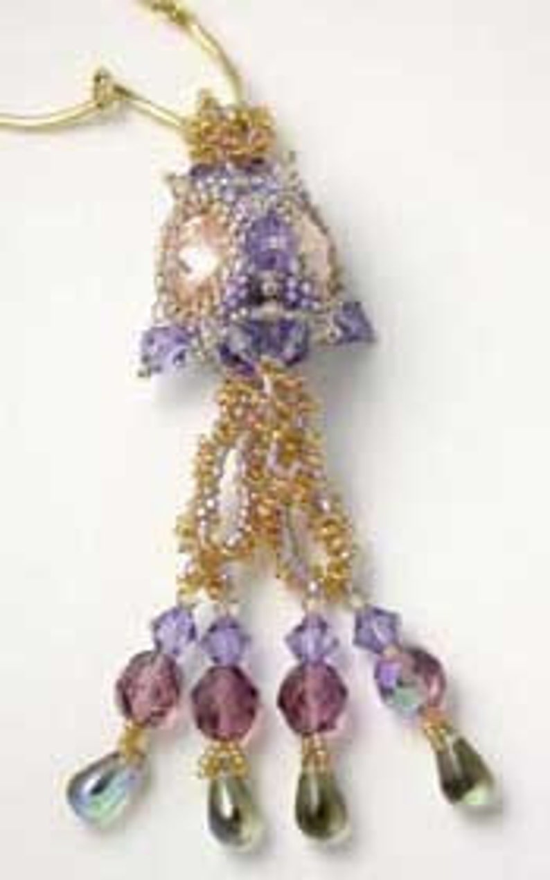 K&ouml;nnte beinhalten: Eine Perlenkette mit einem Anh&auml;nger in Form einer violetten und goldenen Blume und einem herabh&auml;ngenden Kristalltropfen. Der Anh&auml;nger ist aus Perlen gefertigt und hat eine perlmuttartige Mitte.