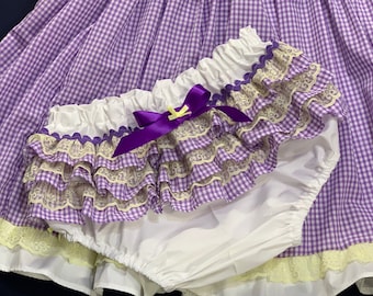 May include: Purple and white gingham fabric with a white ruffle trim and a purple satin bow. The fabric is layered with white lace.