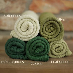 K&ouml;nnte beinhalten: F&uuml;nf gerollte Stoffmuster in verschiedenen Gr&uuml;nt&ouml;nen. Die Farben sind als Soft Green, Olive, Hunter Green, Cactus und Leaf Green beschriftet. Jedes Stoffst&uuml;ck weist eine texturierte, gerippte Oberfl&auml;che auf und ist in einem Stapel angeordnet.