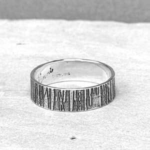 May include: A sterling silver ring with a textured bark-like design. The ring has the word "Annie" engraved on the inside. The word "STERLING" is also engraved on the inside of the ring.