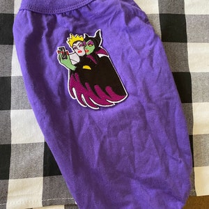 May include: Purple dog t-shirt with an embroidered patch of the Evil Queen and Snow White taking a selfie.
