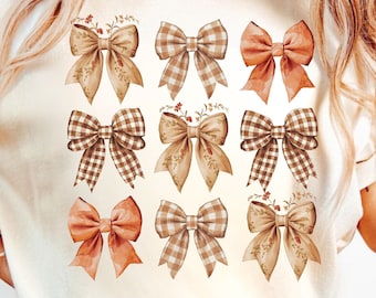 May include: Cream-colored t-shirt featuring a grid of twelve decorative bows in shades of brown, peach, and cream. Some bows have a plaid pattern, while others have floral accents. The shirt is paired with blue jeans.