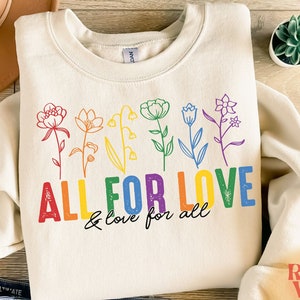 May include: A cream colored sweatshirt with a rainbow design of flowers and the text "ALL FOR LOVE & love for all".