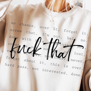 Op de afbeelding: Een beige sweatshirt met de tekst "fuck that" in een vet, zwart lettertype. Rondom de hoofdtekst staan kleinere zinnen als "no chance", "forget it" en "not today". Een casual, comfortabel kledingstuk.