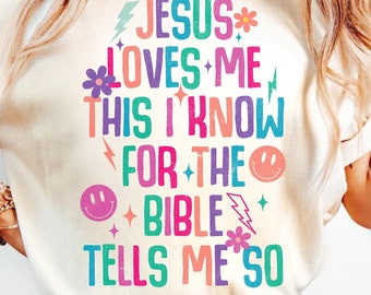 May include: A white t-shirt with a colorful graphic that says "JESUS LOVES ME THIS I KNOW FOR THE BIBLE TELLS ME SO".