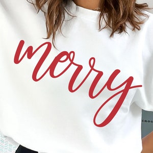 May include: A white sweatshirt with the word "merry" in red cursive script. The casual top is a crew neck style, perfect for the holiday season. The text is large and centered on the front of the garment.