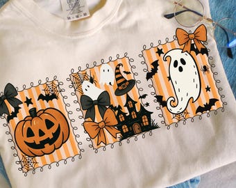 May include: Cream-colored t-shirt with three Halloween-themed designs. Each design features orange and white stripes, a black bow, and a Halloween icon: a jack-o'-lantern, a haunted house, and a ghost. The text "NARADREAMCRAFTS" is at the bottom.