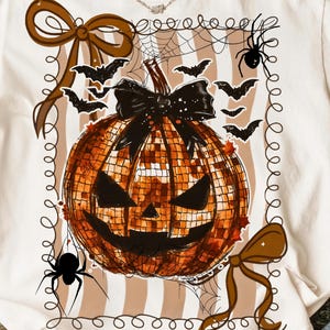 May include: White t-shirt with a Halloween-themed design. The graphic features a disco ball pumpkin with a black bow, surrounded by bats, spiders, and decorative bows. The text "NARADREAMCRAFTS" is at the bottom.