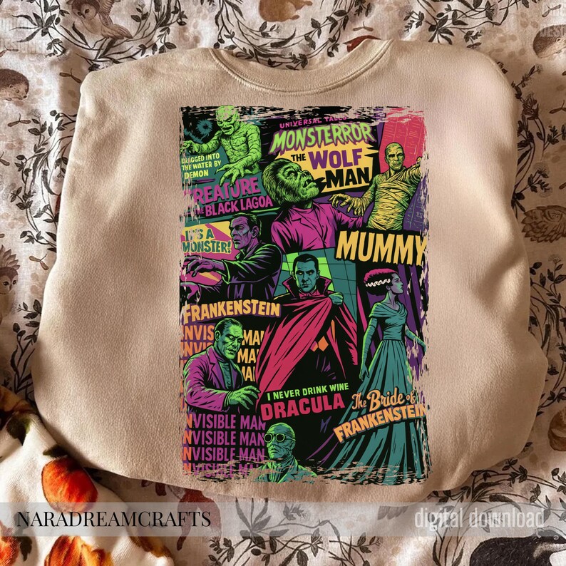May include: Beige sweatshirt featuring a colorful graphic of classic Universal Monsters movie posters. The design includes images of Frankenstein, Dracula, the Mummy, and the Wolfman. Text includes "Monster", "Creature", and "Bride of Frankenstein".