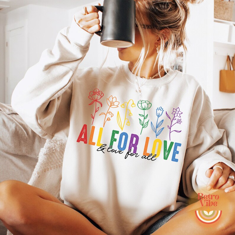 Puede incluir: Una sudadera blanca con un dise&ntilde;o de arco&iacute;ris con flores y el texto "ALL FOR LOVE & love for all".