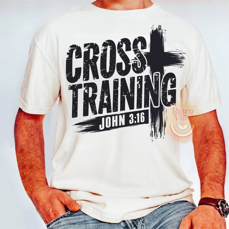 May include: Cream-colored t-shirt with the words "CROSS TRAINING" in distressed black lettering, accompanied by a black cross graphic and the text "JOHN 3:16". The shirt has short sleeves and a crew neck.