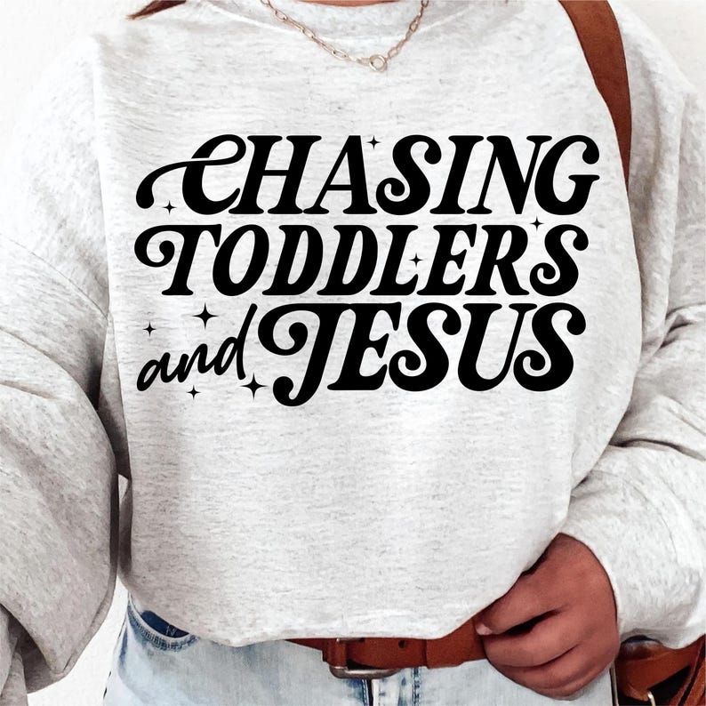 May include: A gray sweatshirt with the text "CHASING TODDLERS and JESUS" in black retro-style lettering.