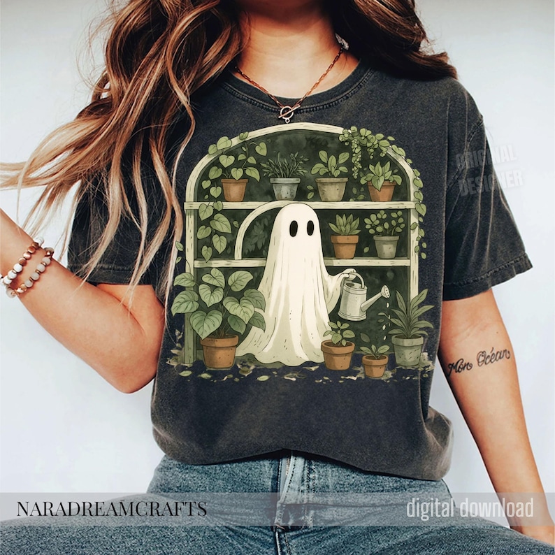 K&ouml;nnte beinhalten: Dunkelgraues T-Shirt mit einer skurrilen Illustration eines Geistes, der Pflanzen in einem Gew&auml;chshaus gie&szlig;t. Der Geist ist wei&szlig;, und die Pflanzen sind gr&uuml;n mit braunen T&ouml;pfen. Der Text "NARADREAMCRAFTS" befindet sich unten.
