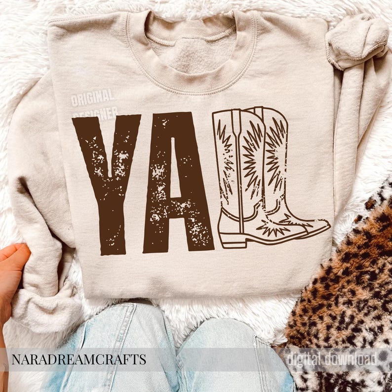 May include: Beige sweatshirt with the word "YA'LL" in distressed brown letters and a matching illustration of cowboy boots. The text "ORIGINAL DESIGNER" is printed above the word "YA'LL".