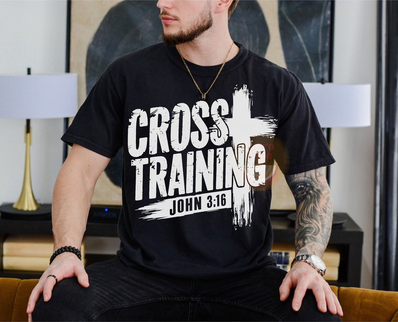 May include: Black t-shirt with the words "CROSS TRAINING" in a bold, white font, accompanied by a white cross graphic. The text "JOHN 3:16" is below the main text. The shirt is a casual wear item.