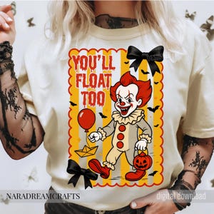Op de afbeelding: Cr&egrave;mekleurig T-shirt met een cartoonclown met rood haar en make-up, met een rode ballon en een pompoen-lantaarn. De tekst "YOU'LL FLOAT TOO" is oranje weergegeven. Zwarte vleermuizen en strikken versieren het ontwerp, perfect voor Halloween.