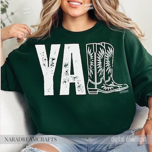 May include: Dark green sweatshirt with the word "YA" in distressed white letters and a white outline of cowboy boots. The text "NARADREAMCRAFTS" is at the bottom.